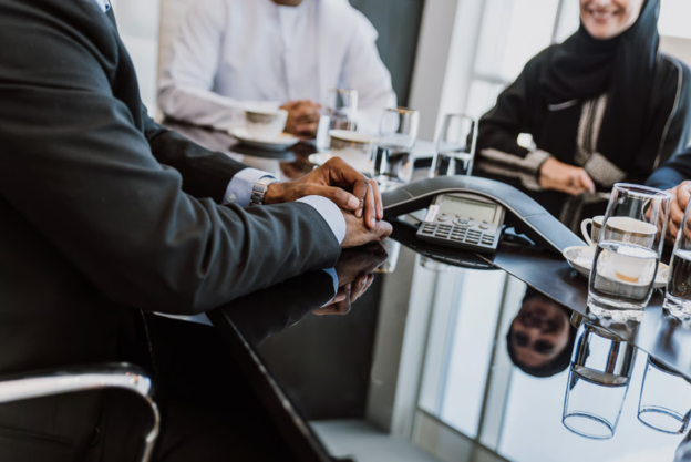 Business team in a meeting using a conference phone, highlighting how the right business phone system supports clear communication, scalability and reliable customer service.