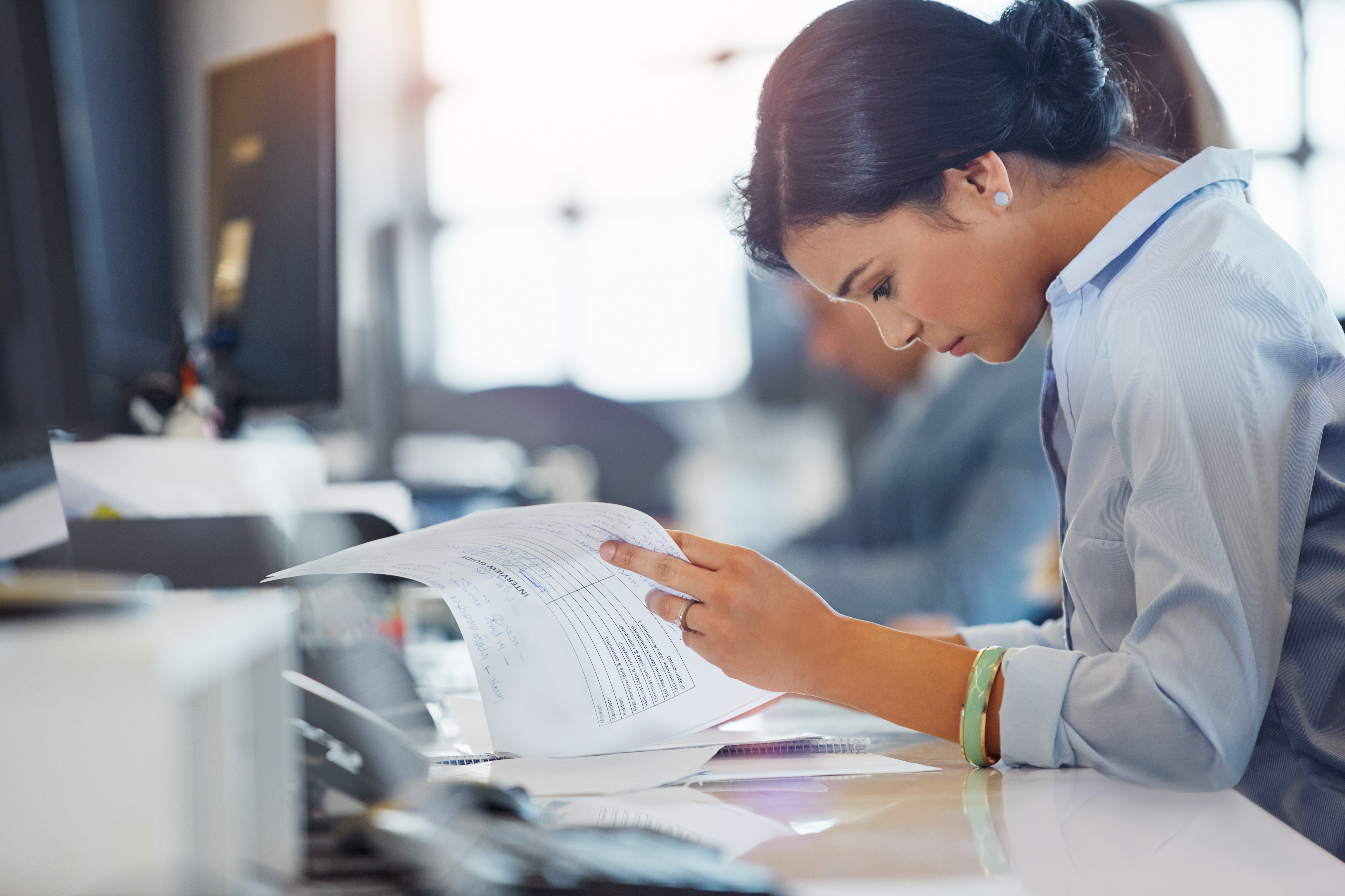 Finance professional reviewing paper invoices manually, highlighting the hidden cost of slow processing, errors and admin time for finance teams.